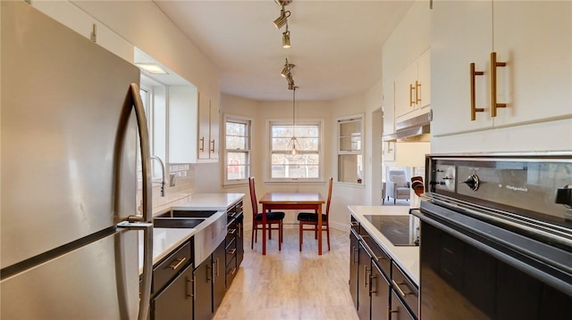 kitchen with hanging light fixtures, decorative backsplash, black appliances, and white cabinets