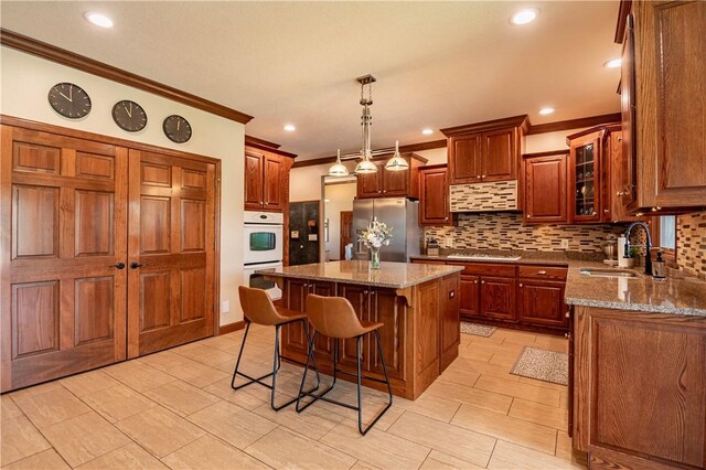 kitchen featuring a sink, decorative backsplash, ornamental molding, double oven, and freestanding refrigerator