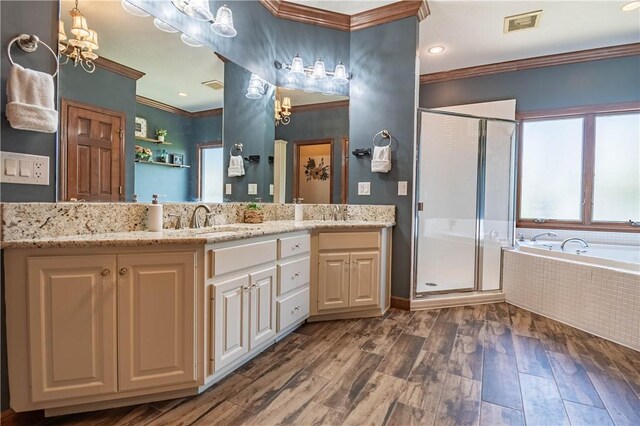 full bathroom with crown molding, a stall shower, a bath, wood finished floors, and vanity