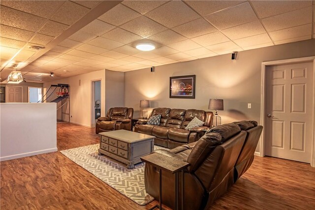 living area with a drop ceiling, wood finished floors, and baseboards
