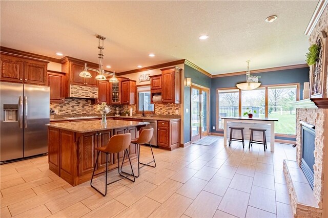 kitchen with a breakfast bar area, tasteful backsplash, appliances with stainless steel finishes, a center island, and brown cabinetry