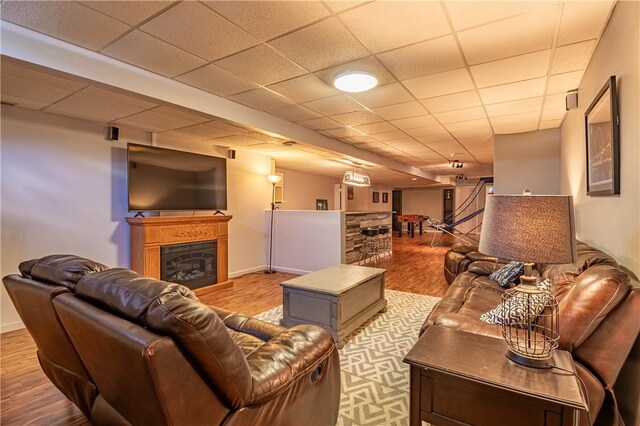 living area with baseboards, wood finished floors, a bar, and a glass covered fireplace