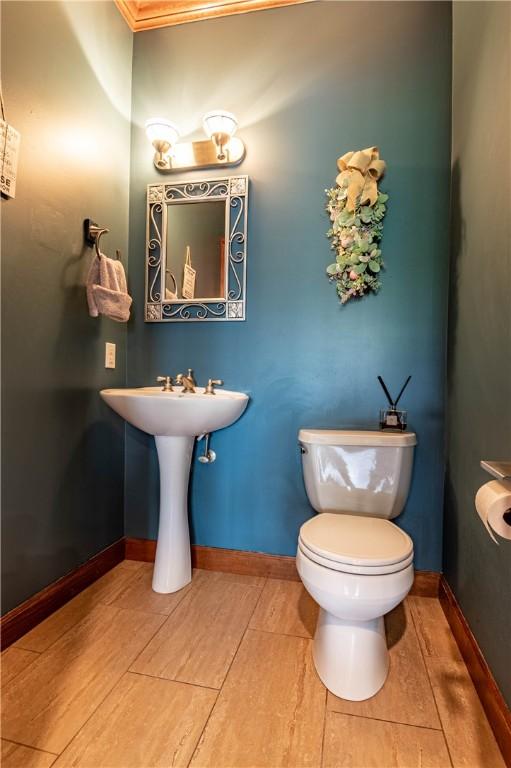 half bathroom featuring baseboards, wood finished floors, and toilet