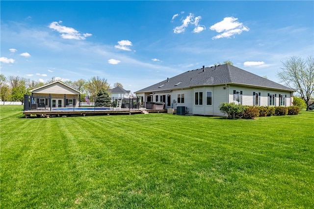 rear view of property featuring a yard, a fenced in pool, and a deck