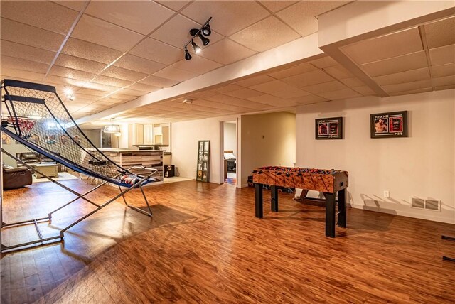 rec room with visible vents, a drop ceiling, wood finished floors, and baseboards