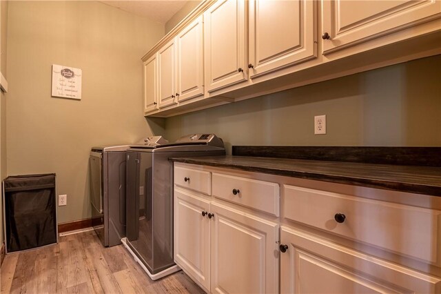laundry area with light wood finished floors, washing machine and clothes dryer, cabinet space, and baseboards