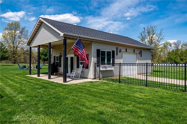 view of front of house with a front yard, a shingled roof, a patio area, and fence