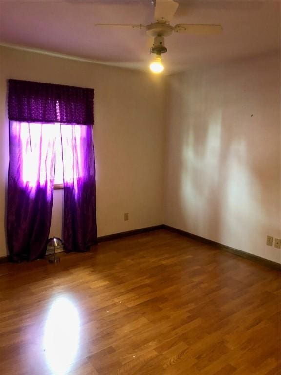 unfurnished room featuring ceiling fan, baseboards, and wood finished floors