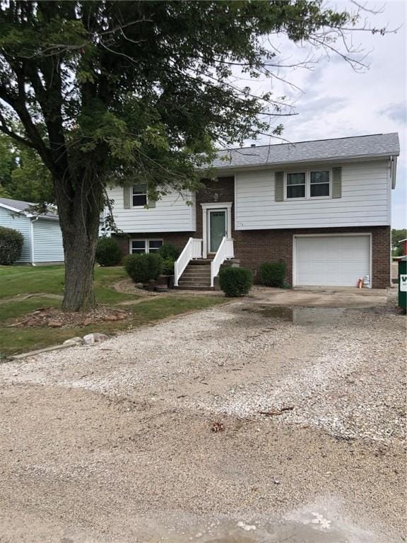 split foyer home featuring driveway, an attached garage, and brick siding