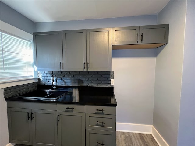 kitchen featuring gray cabinetry, backsplash, and hardwood / wood-style floors