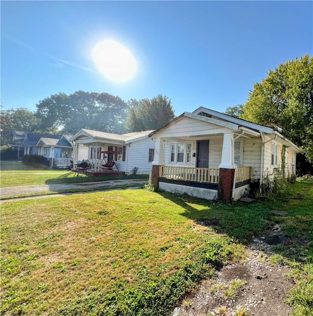 bungalow featuring covered porch and a front lawn