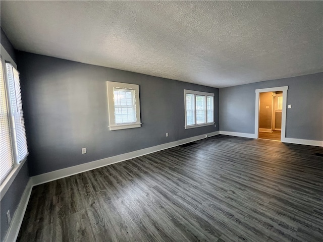 empty room with dark wood-type flooring and a textured ceiling