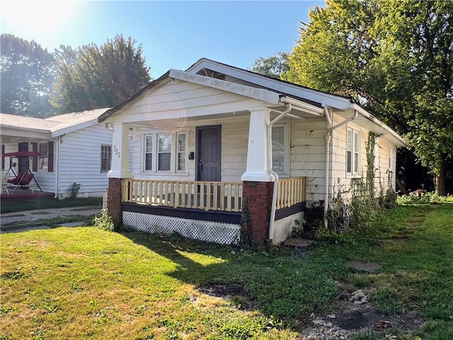 bungalow-style home featuring covered porch and a front yard