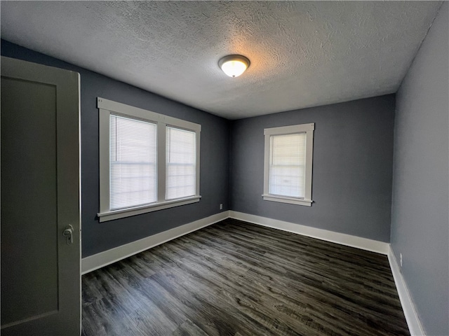 empty room with a textured ceiling, dark hardwood / wood-style floors, and a healthy amount of sunlight