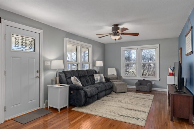 living room with dark wood-type flooring, plenty of natural light, and ceiling fan