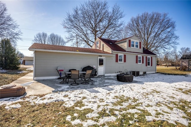 snow covered rear of property with a patio, cooling unit, and an outdoor fire pit