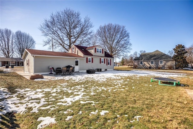 rear view of property featuring a trampoline, a patio area, and a lawn