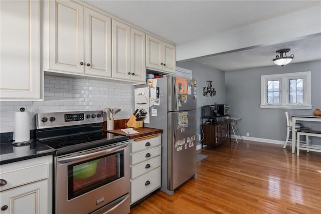 kitchen with appliances with stainless steel finishes, backsplash, and light wood-type flooring