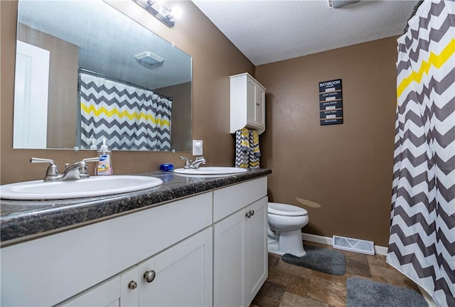 bathroom featuring vanity, a textured ceiling, and toilet