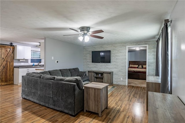 living room with hardwood / wood-style flooring, a barn door, sink, and ceiling fan