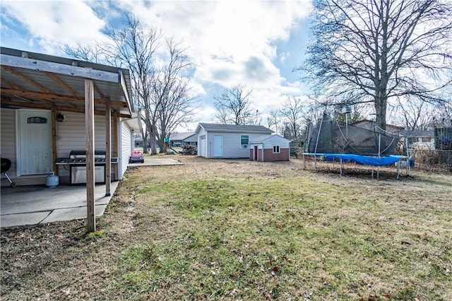 view of yard featuring a trampoline, a patio, and a storage unit