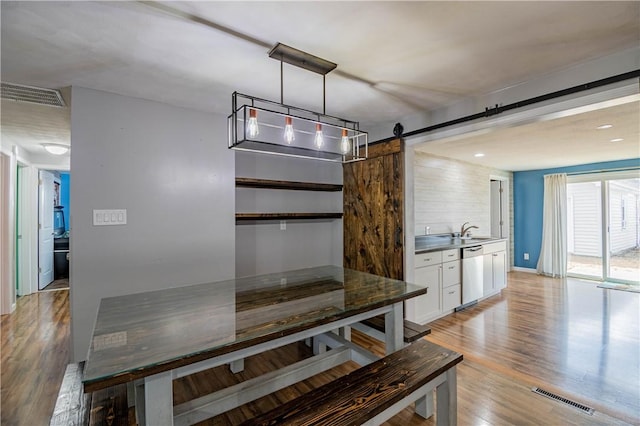 dining room with sink, a barn door, and light hardwood / wood-style floors