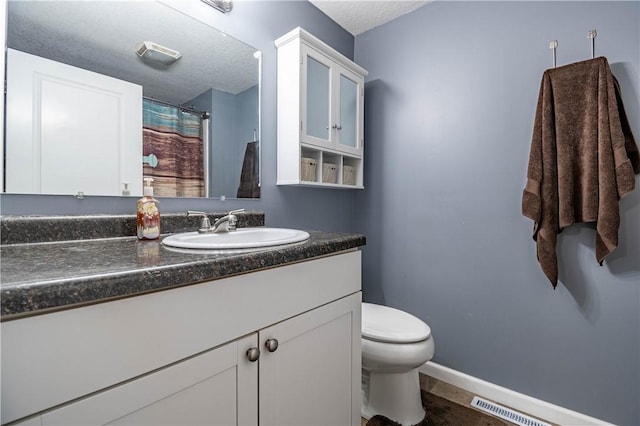 bathroom with vanity, toilet, and a textured ceiling