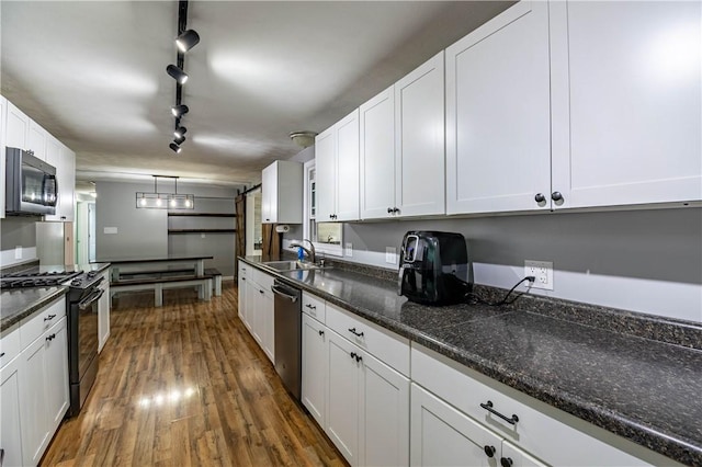 kitchen with decorative light fixtures, white cabinetry, sink, stainless steel appliances, and dark wood-type flooring