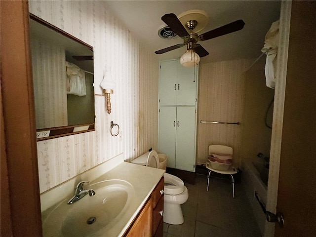 bathroom with a bathtub, vanity, tile patterned flooring, ceiling fan, and toilet