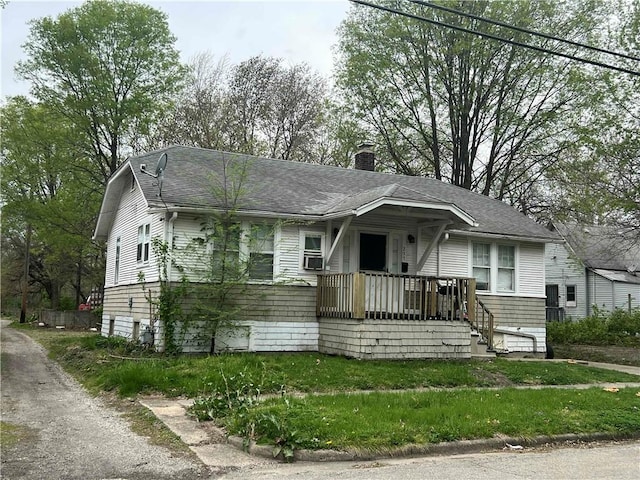 view of front facade featuring a shingled roof and a chimney