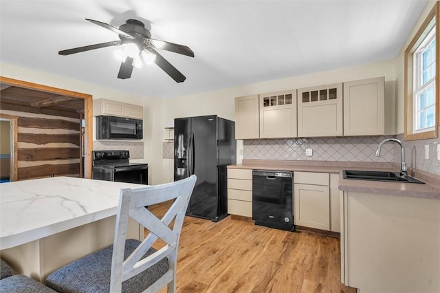 kitchen with black appliances, light hardwood / wood-style floors, decorative backsplash, sink, and cream cabinets