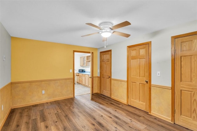 spare room featuring ceiling fan, light hardwood / wood-style flooring, and wooden walls