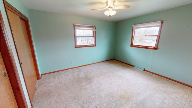 unfurnished bedroom featuring multiple windows, ceiling fan, and light colored carpet