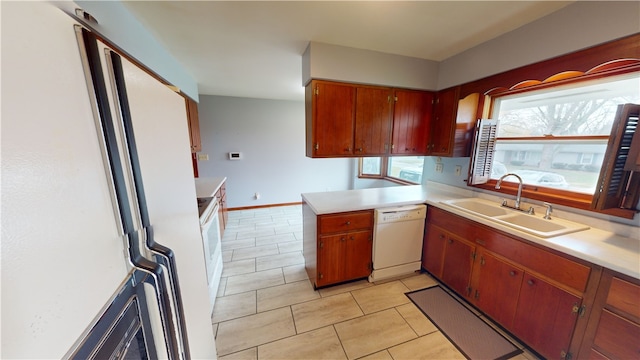 kitchen featuring kitchen peninsula, white appliances, sink, and light tile patterned floors