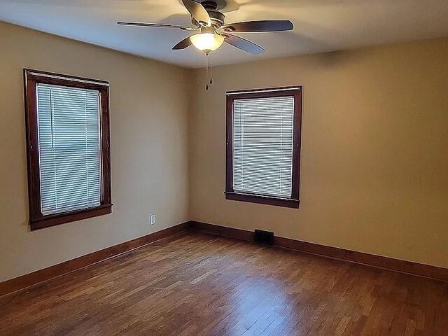 203 N E St, Olney, IL 62450 - spare room featuring dark wood-style flooring, a ceiling fan, and baseboards