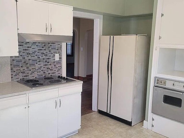 203 N E St, Olney, IL 62450 - kitchen with white appliances, under cabinet range hood, white cabinets, and light countertops