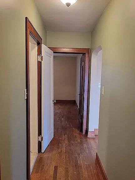 203 N E St, Olney, IL 62450 - hallway featuring dark wood-type flooring, arched walkways, and baseboards