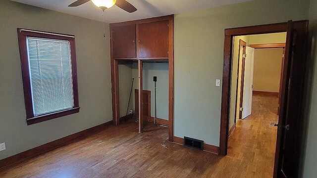 203 N E St, Olney, IL 62450 - unfurnished bedroom with light wood-style flooring, baseboards, a closet, and a ceiling fan