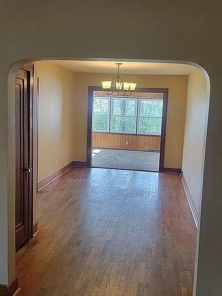 203 N E St, Olney, IL 62450 - unfurnished room with arched walkways, wood finished floors, a chandelier, and healthy amount of natural light