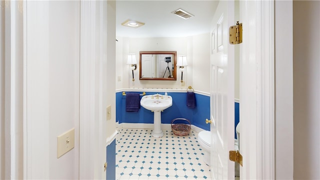 half bath featuring baseboards, visible vents, toilet, and tile patterned floors