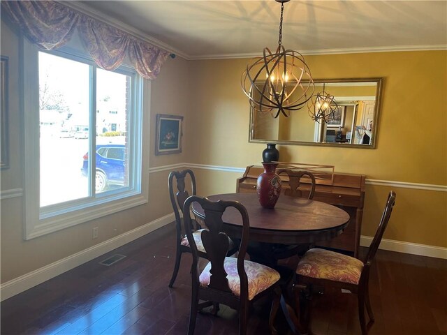 dining area with hardwood / wood-style flooring, crown molding, and an inviting chandelier