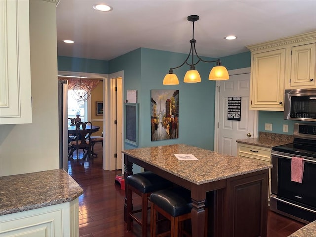 kitchen featuring a center island, dark wood-style flooring, a breakfast bar, stainless steel appliances, and recessed lighting