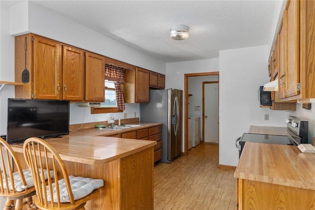 11444 N 800th St, Effingham, IL 62401 - kitchen featuring appliances with stainless steel finishes, washer and clothes dryer, a peninsula, brown cabinets, and a breakfast bar