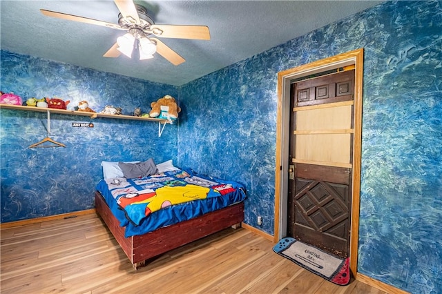 10622 N Rte 121, Latham, IL 62543 - bedroom featuring wallpapered walls, wood finished floors, a textured ceiling, a ceiling fan, and baseboards