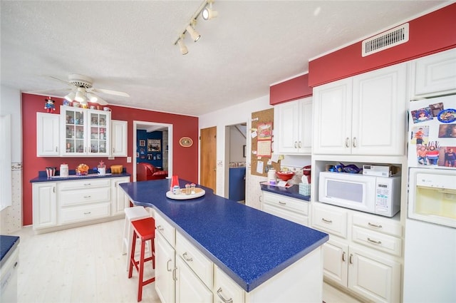 18 Woodmere Dr, Paris, IL 61944 - kitchen featuring white appliances, dark countertops, a center island, a textured ceiling, and white cabinets