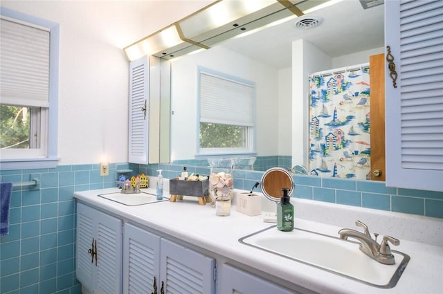 18 Woodmere Dr, Paris, IL 61944 - bathroom featuring plenty of natural light, tile walls, double vanity, a wainscoted wall, and curtained shower