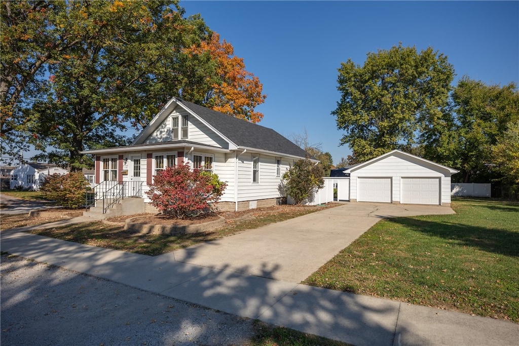 view of front of house with a front yard, a garage, and an outdoor structure