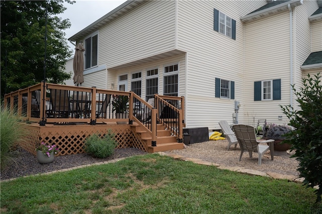 back of property featuring a deck and a lawn