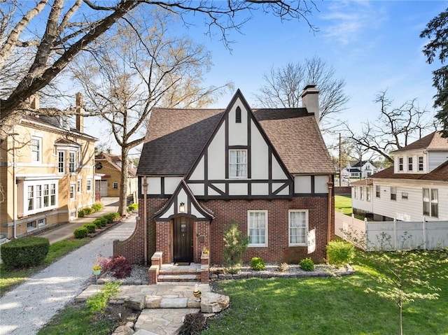 view of front of home with a chimney, stucco siding, brick siding, fence, and a shingled roof