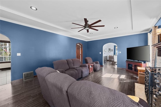 living area featuring wood finished floors, ceiling fan, visible vents, and arched walkways